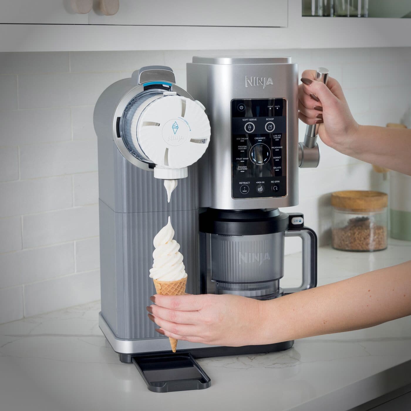Ninja CREAMi dispensing soft serve into a cone using the motorized swirl function.